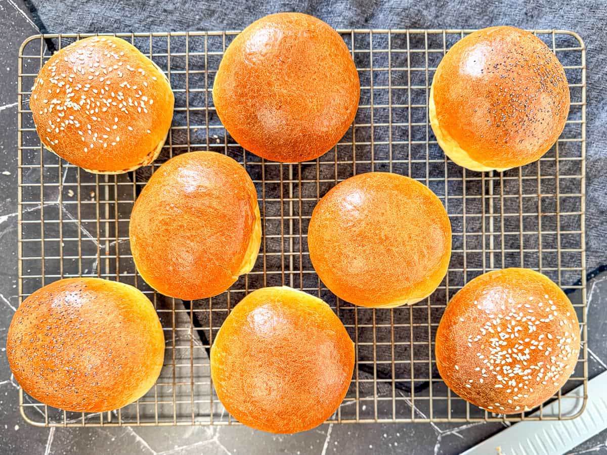 Brioche buns on a wire rack.