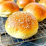 Brioche buns on a wire rack.
