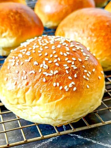 Brioche buns on a wire rack.
