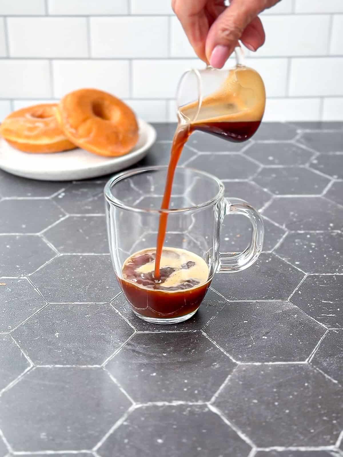 Pouring espresso into a glass mug.