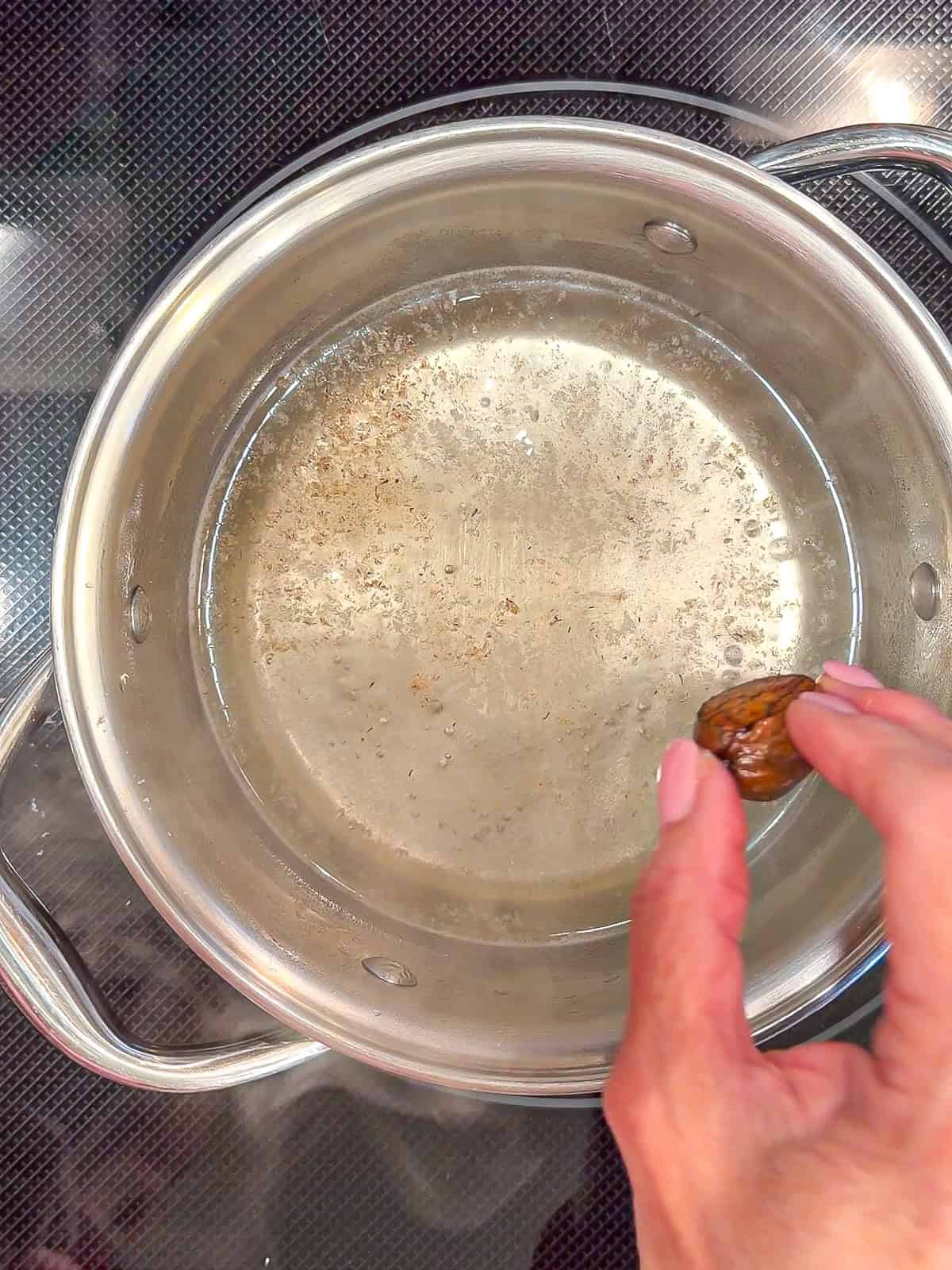 Placing a whole nutmeg into simple syrup.