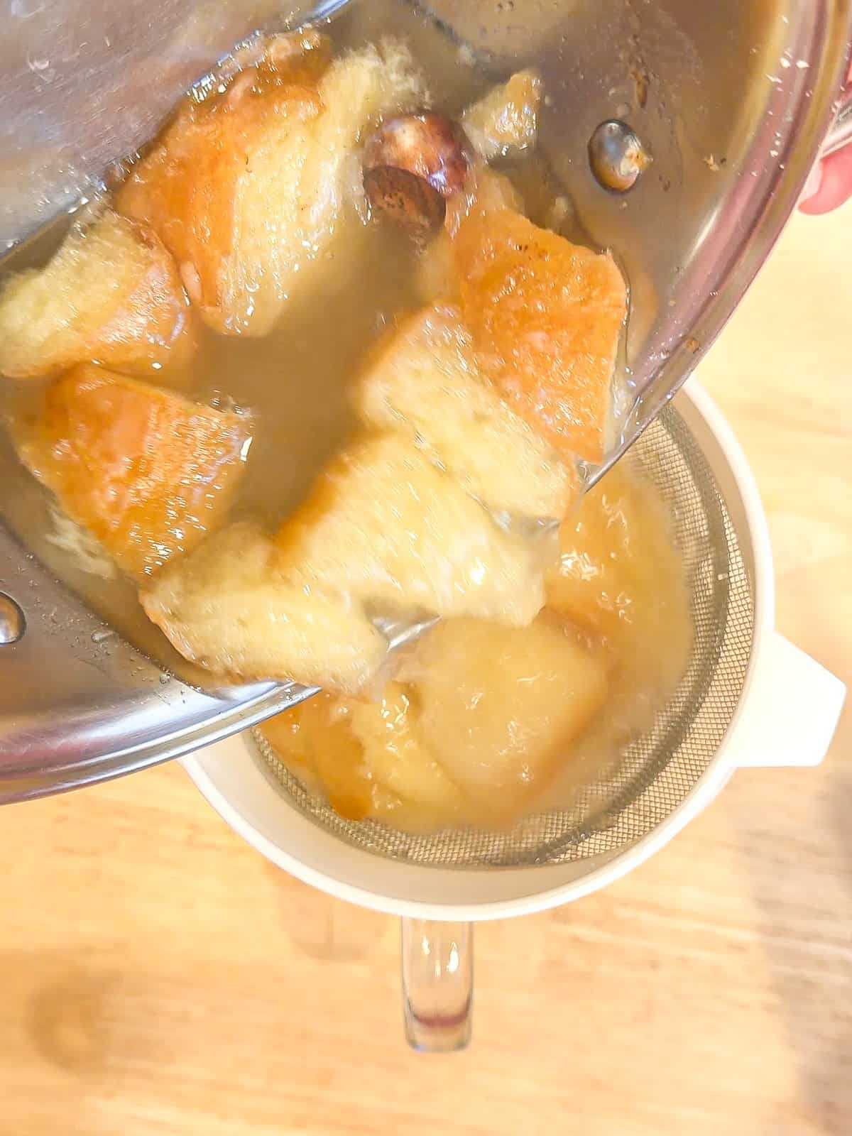 Straining glazed donuts simple syrup with a wire mesh strainer.