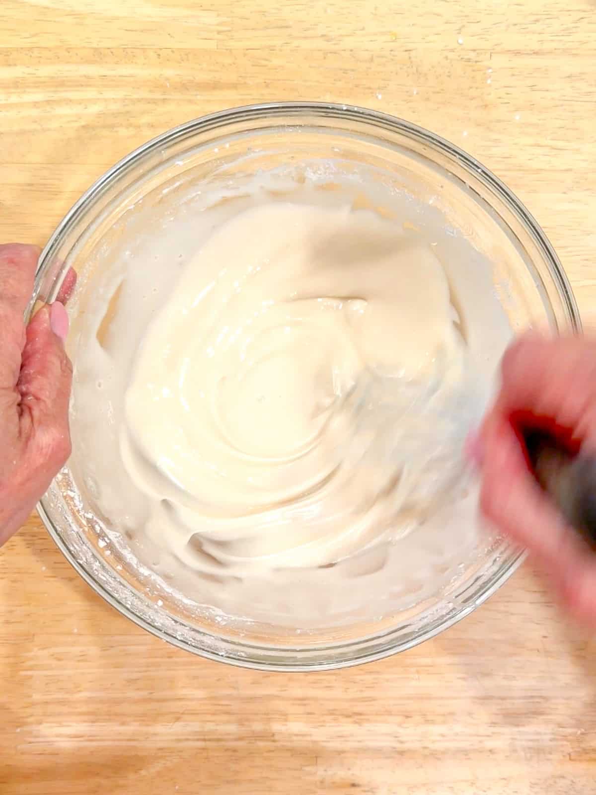 Whisking powdered sugar and milk to make a glaze.