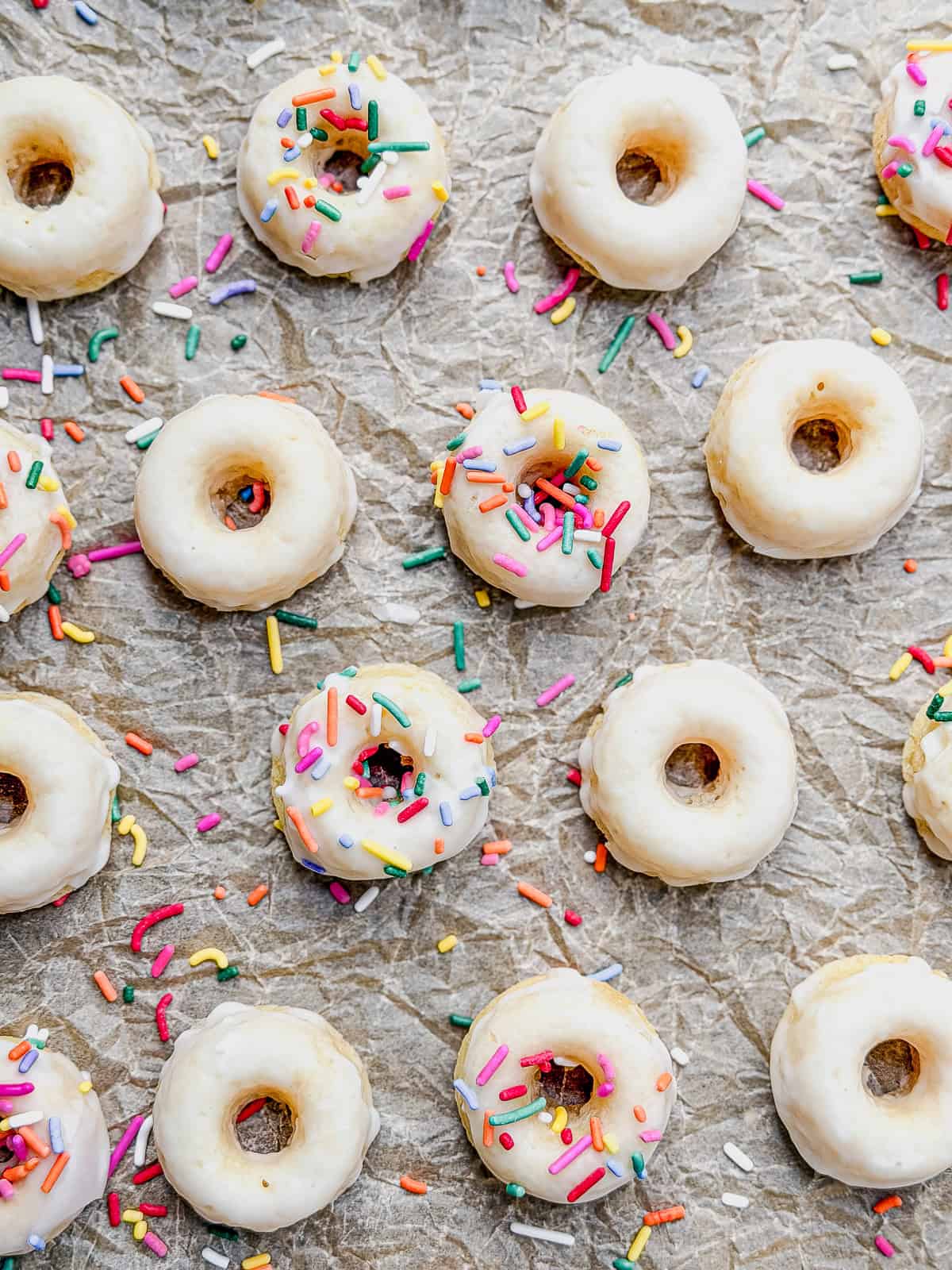 Baked glazed mini donuts on parchment paper.