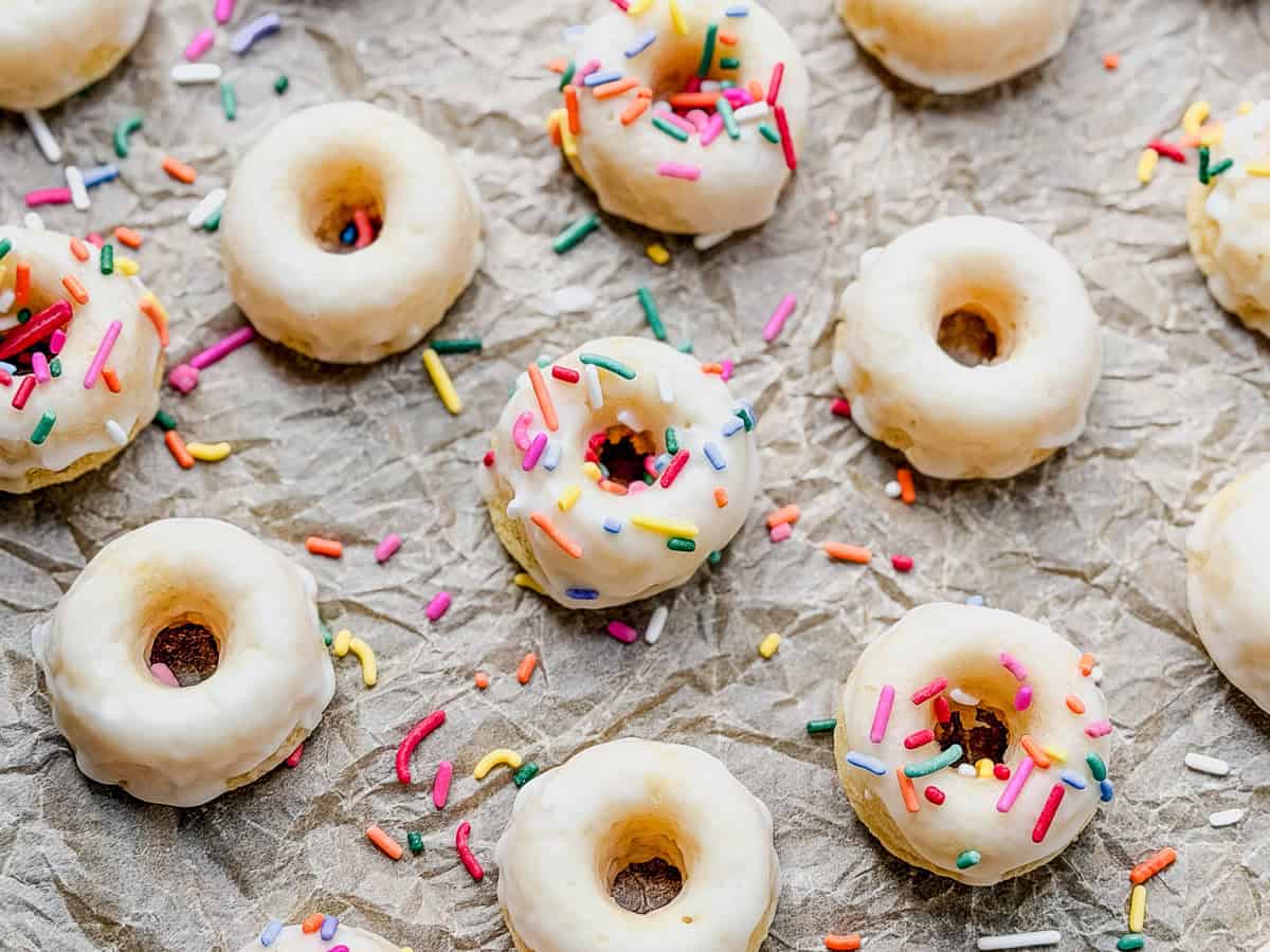 Baked glazed mini donuts on parchment paper.