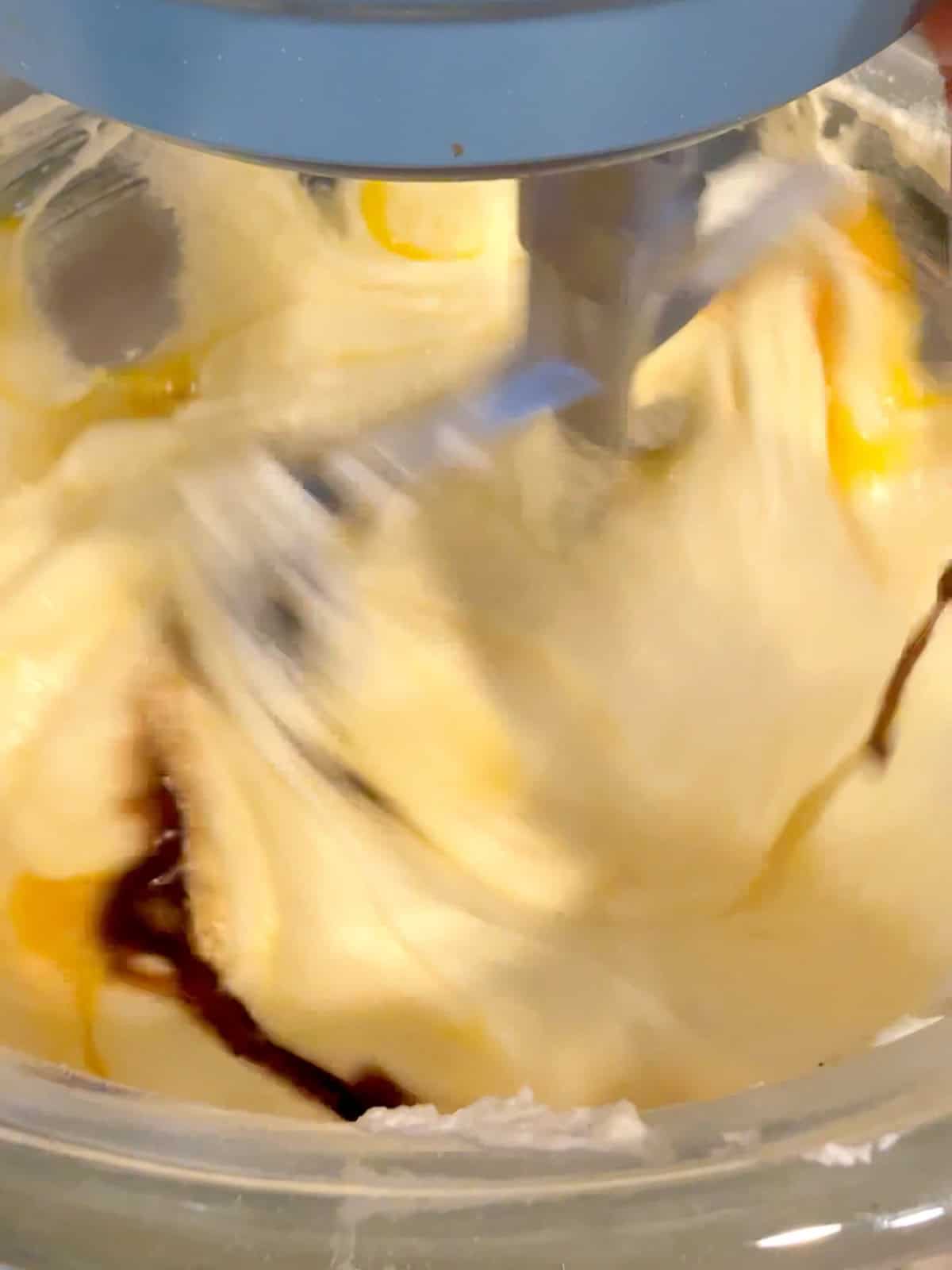 Adding eggs and vanilla to creamed butter and sugar in a stand mixer.