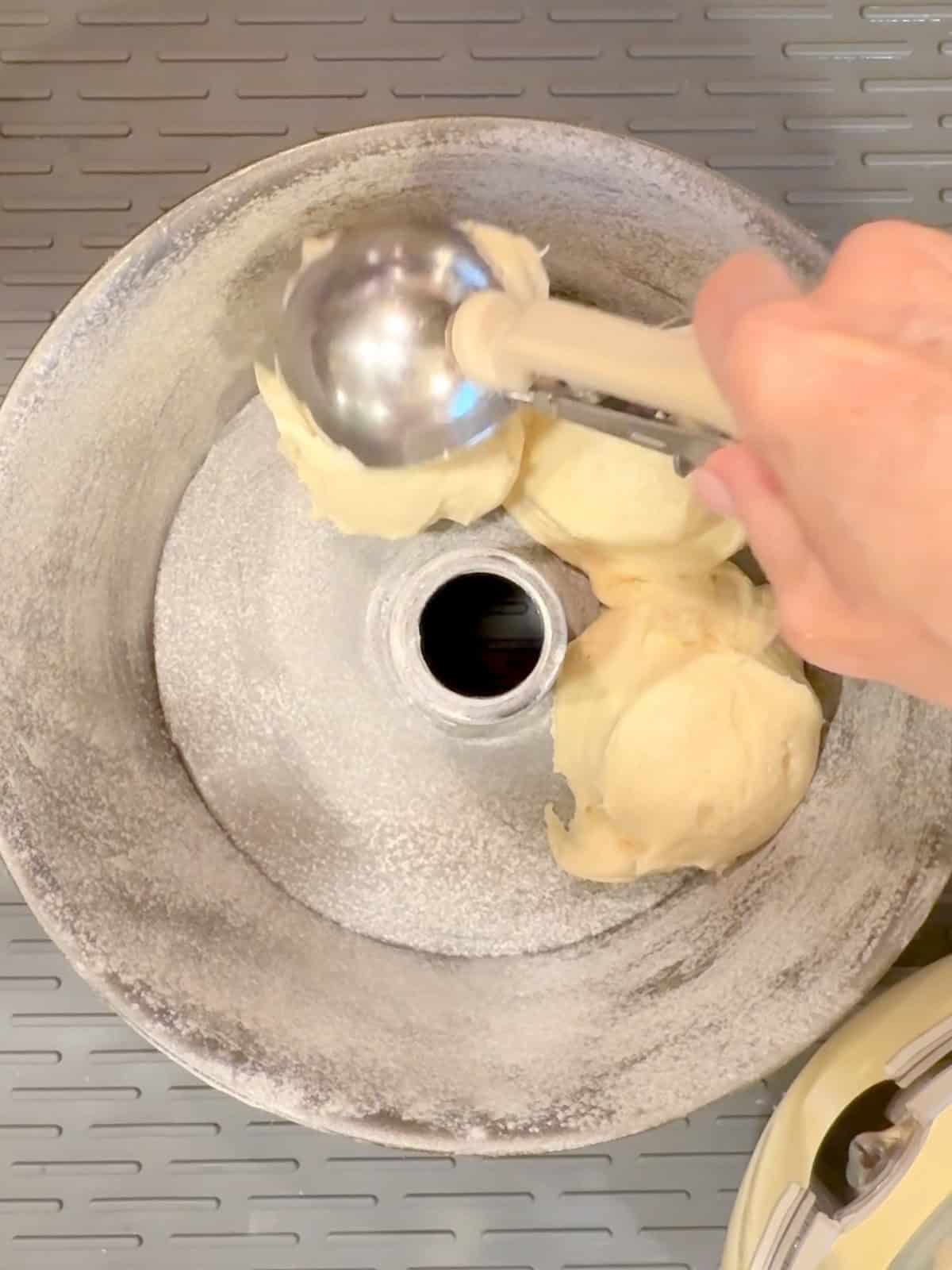 Scooping pound cake batter into a tube pan.