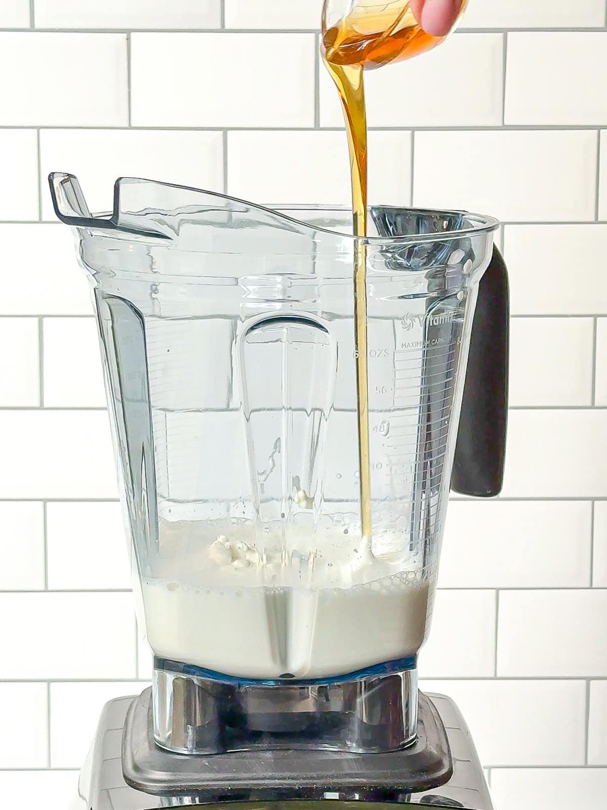 Pouring honey into a blender.