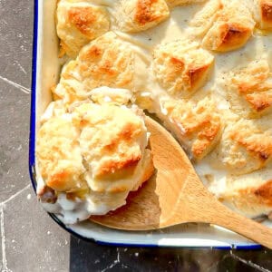 Wooden spoon holding biscuits and gravy casserole.