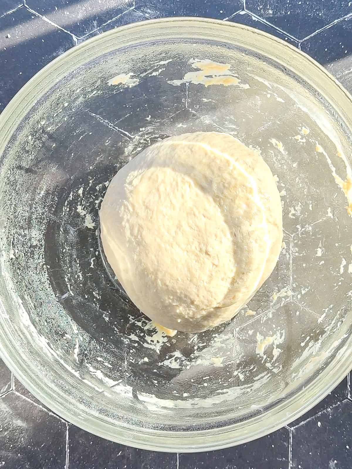 Dinner roll dough in a glass bowl before the first rise.