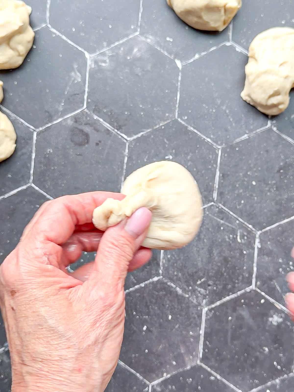 Pinching the edges of a ball of dough together at the top.
