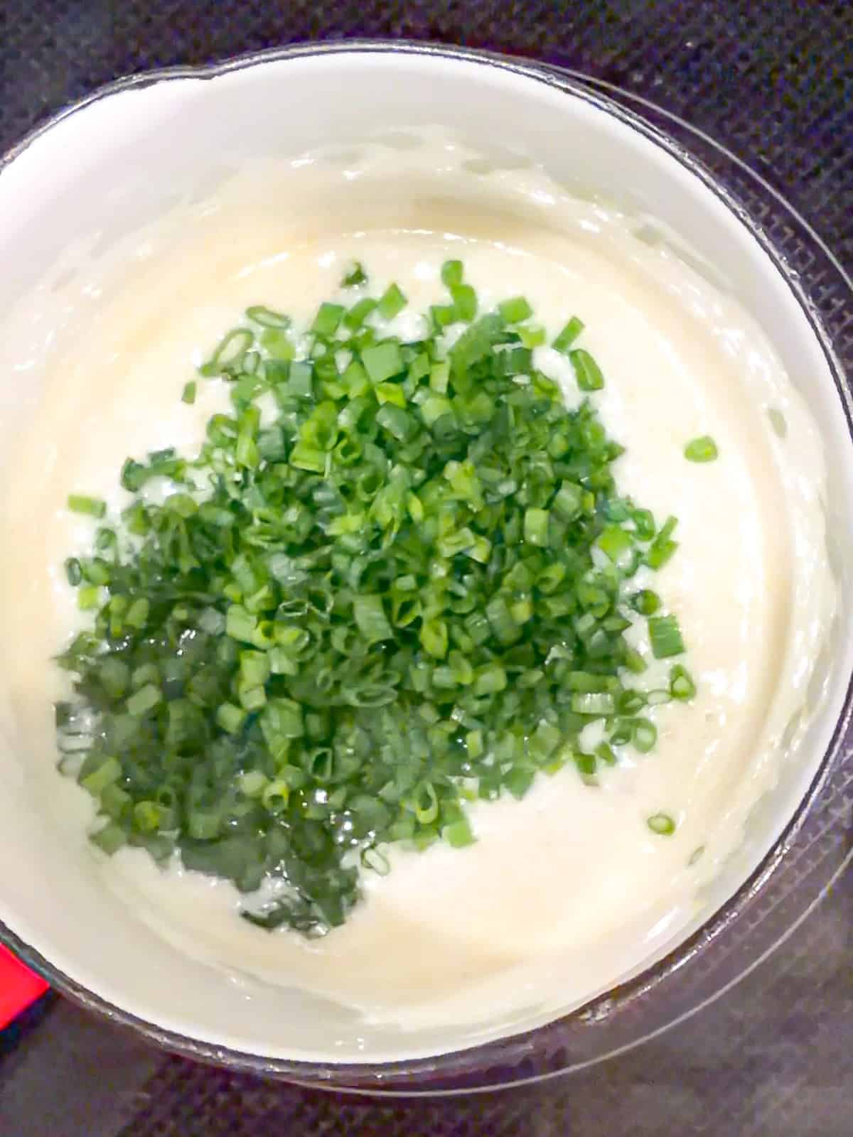Adding fresh chopped chives into sizzling butter in a sauce pan.