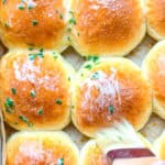 Brushing chive butter on warm dinner rolls.