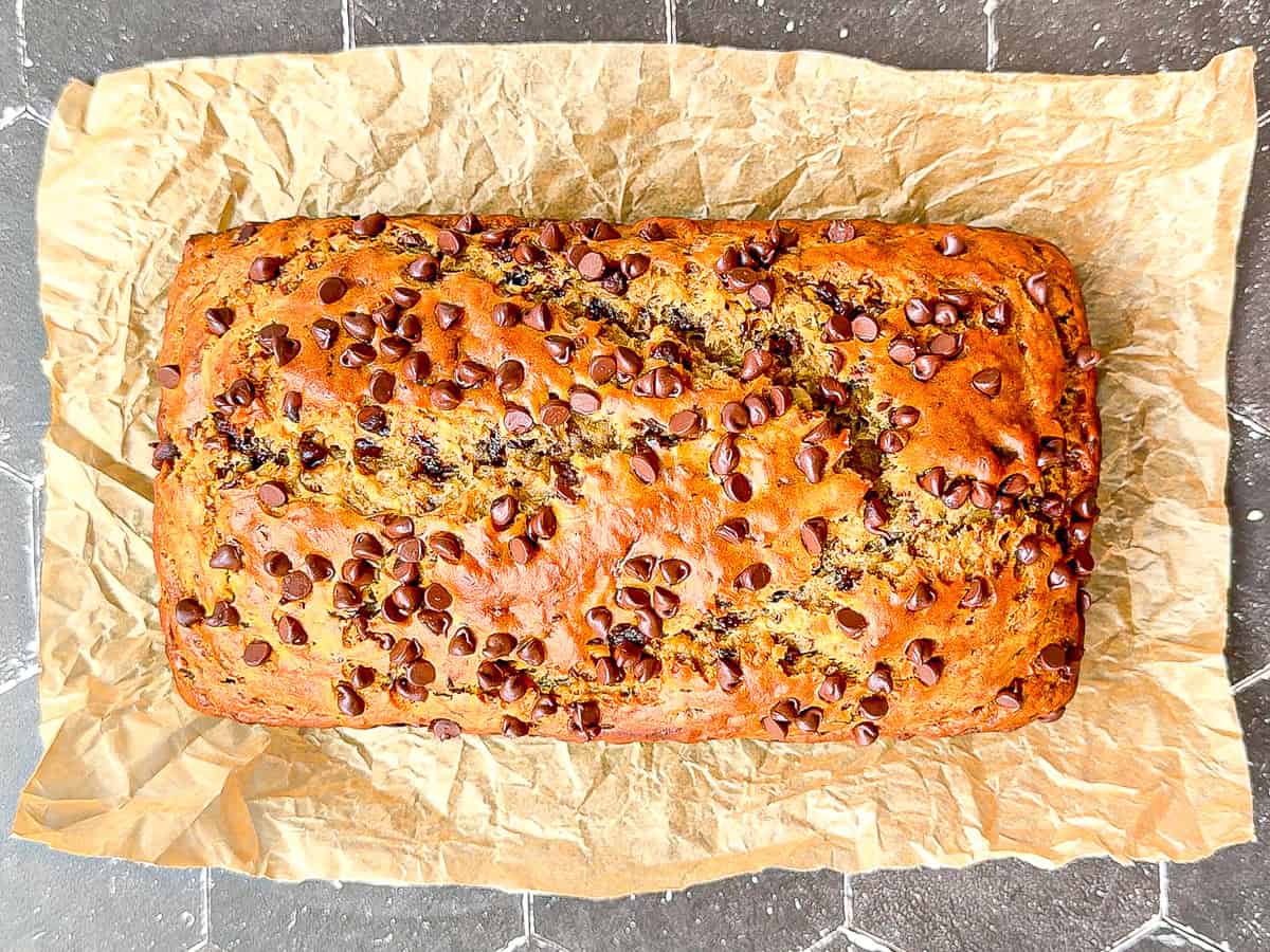 Banana bread on parchment paper on a black tile counter.