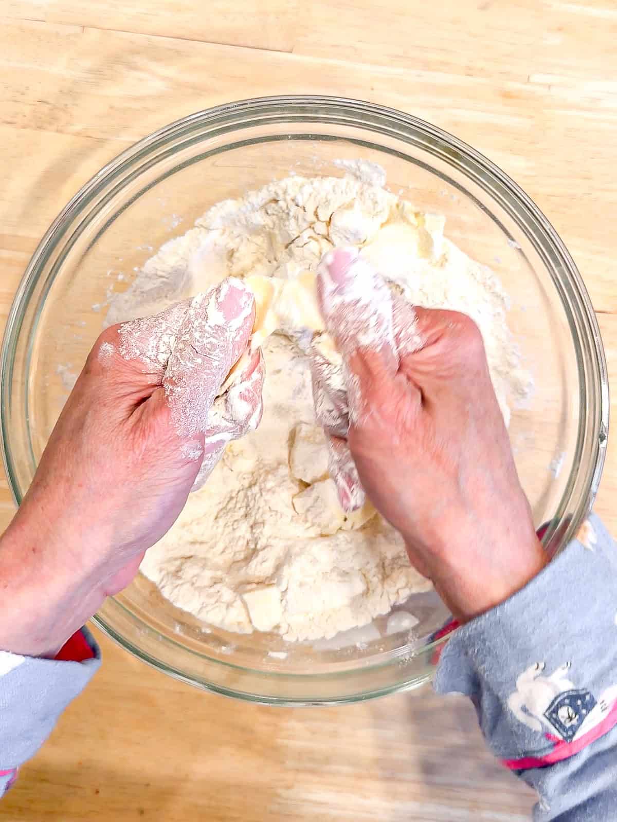 Using fingers and thumbs to rub butter into flour.