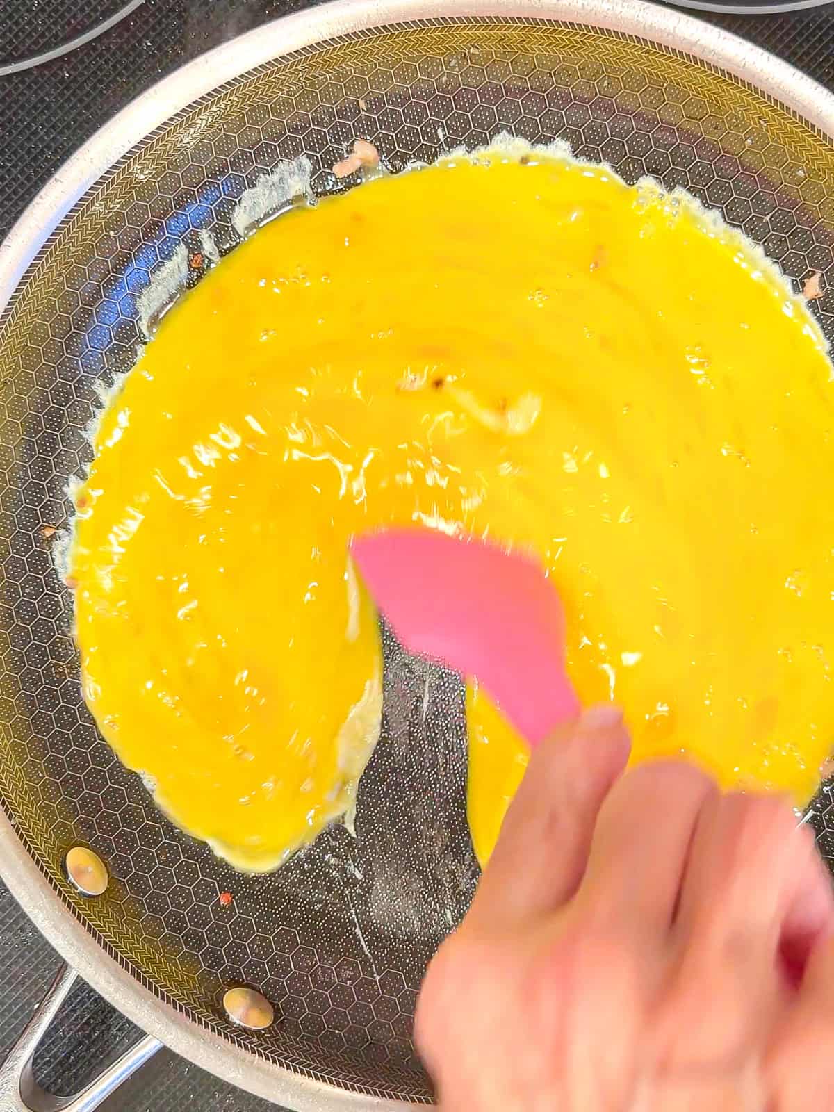 Scrambling eggs in a pan.