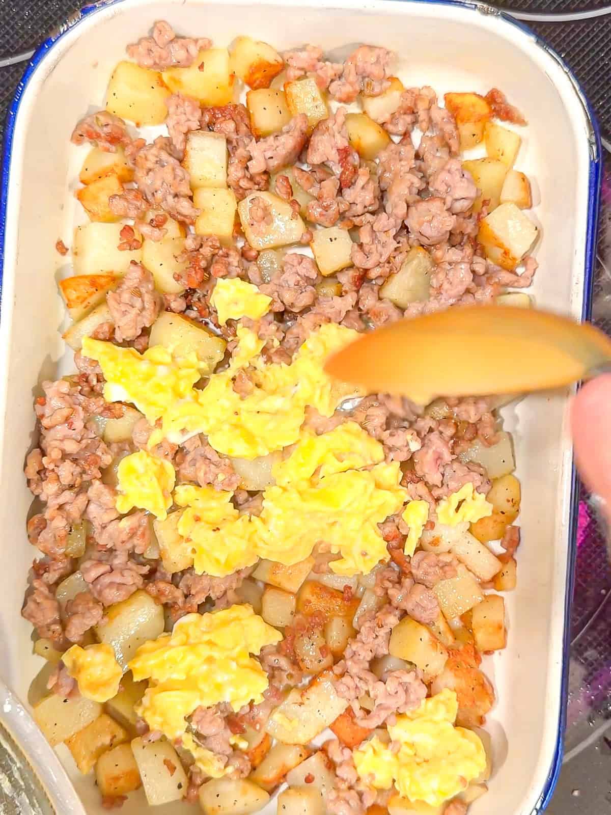 Spooning eggs over other ingredients in a casserole dish.