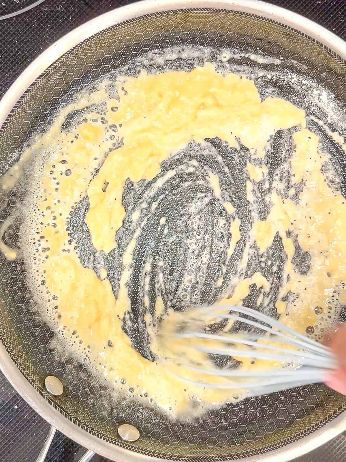 Whisking flour and butter to make a roux.