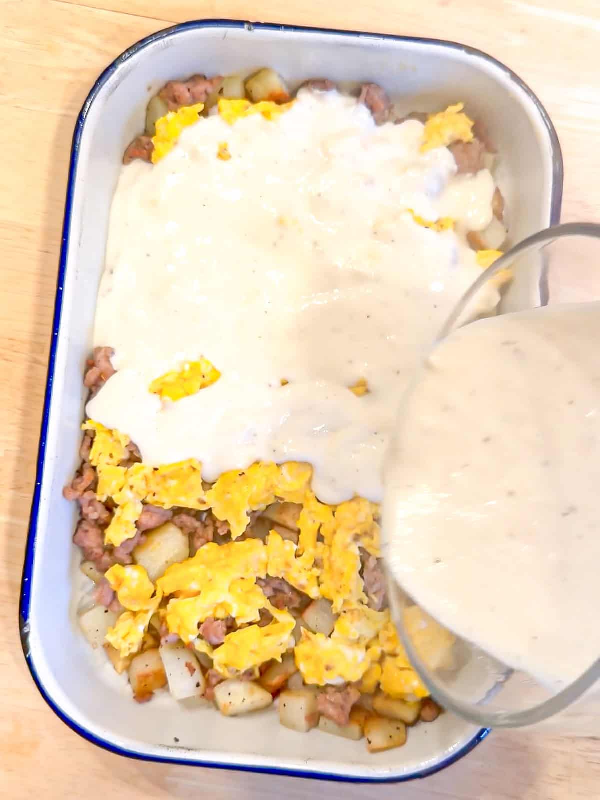 Pouring gravy over a casserole.