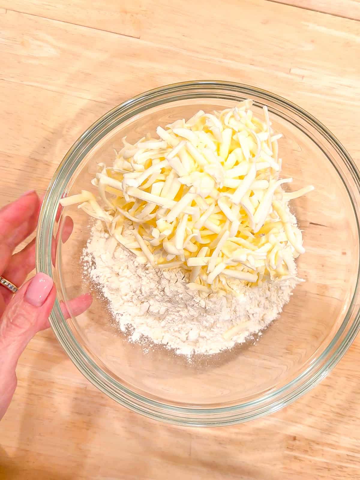 Adding grated butter to self rising flour in a glass bowl.
