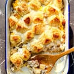 A wooden spoon and a breakfast casserole in a white casserole dish.