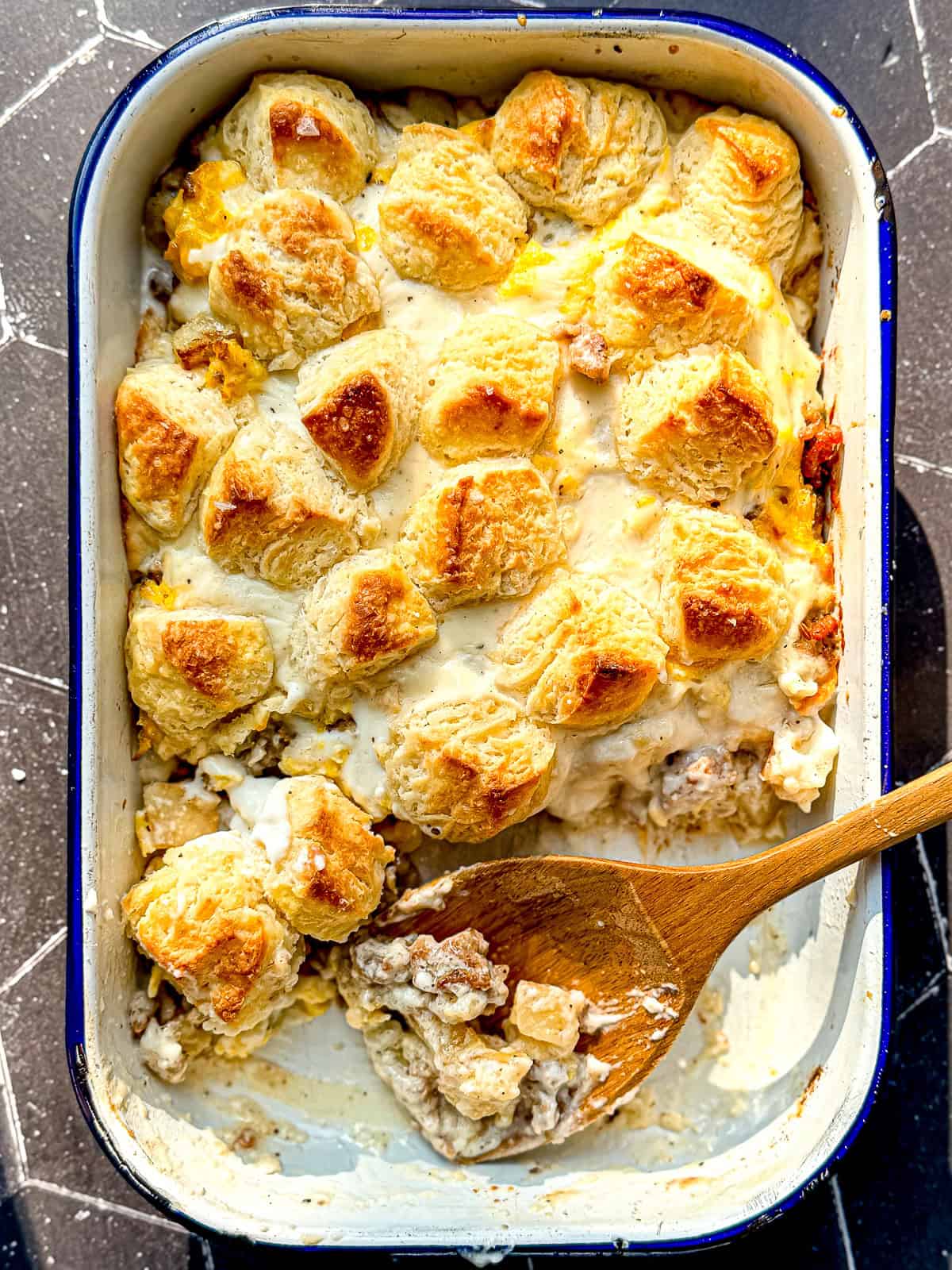 A wooden spoon and a breakfast casserole in a white casserole dish.