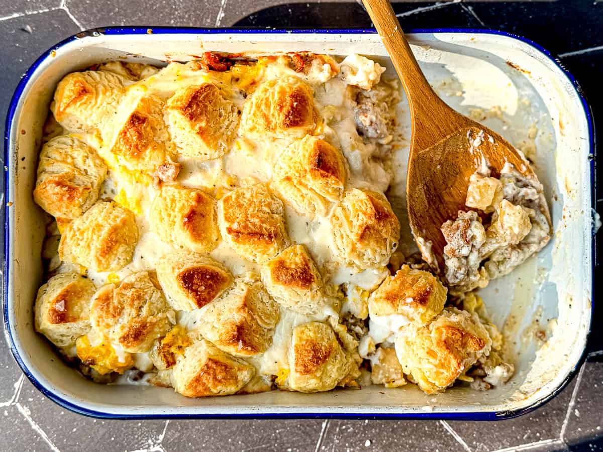 A wooden spoon and a breakfast casserole in a white casserole dish.