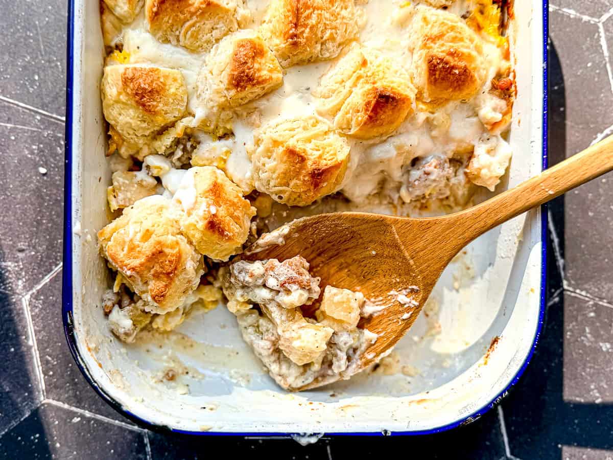 A wooden spoon and a breakfast casserole in a white casserole dish.