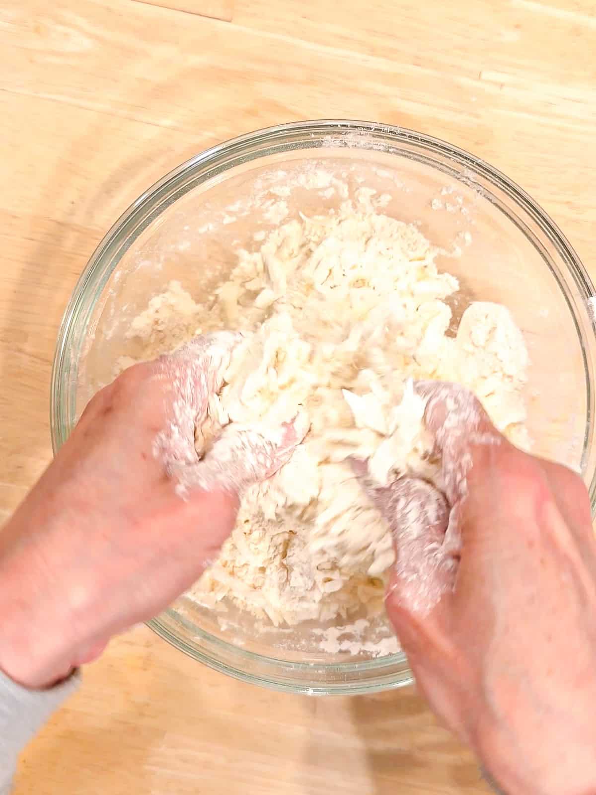 Cutting butter into self rising flour in a glass bowl.