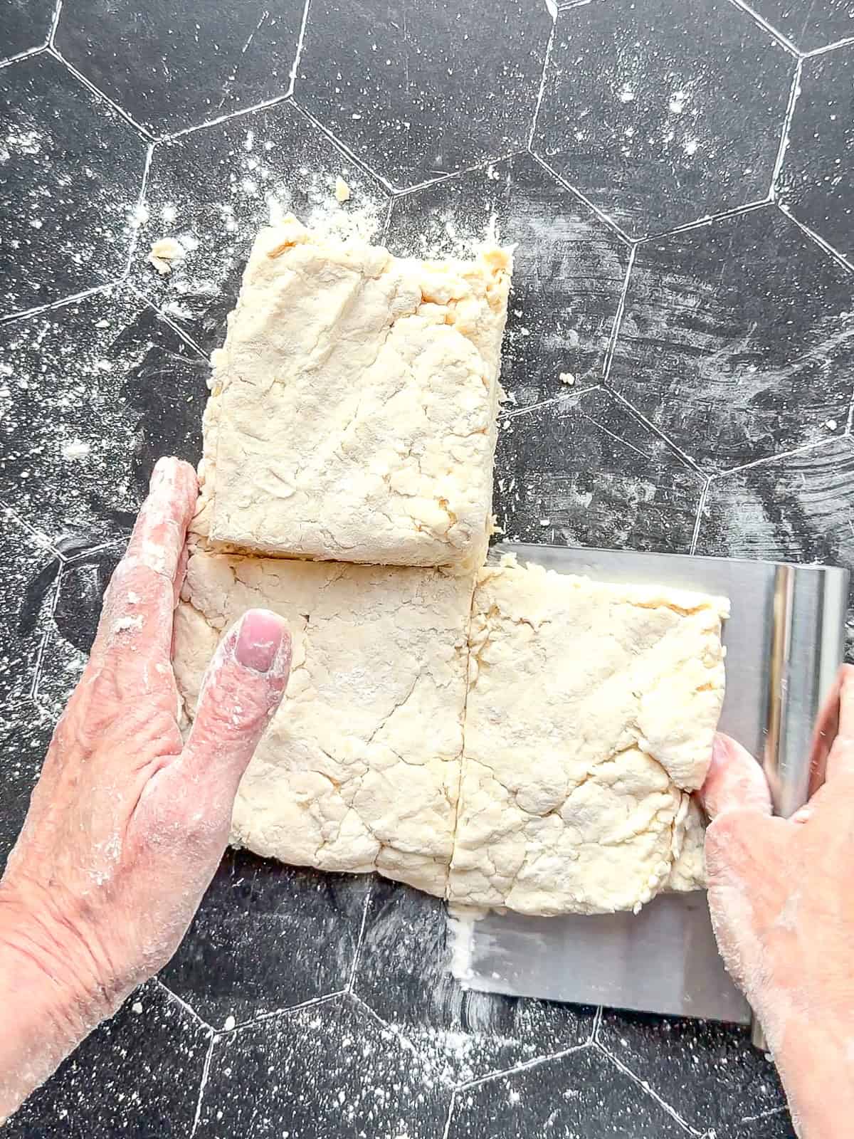 Stacking squares of biscuit dough on top of each other.