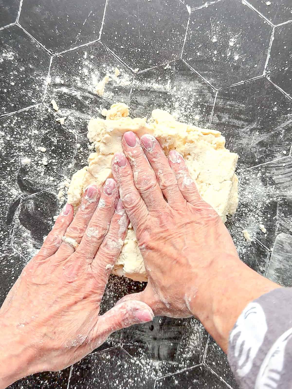 Pressing biscuit dough out into a square.