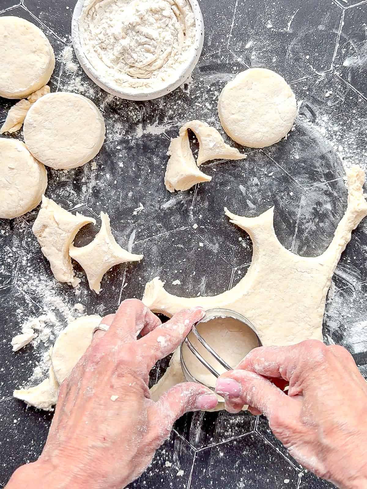 Cutting out biscuits on a black counter.