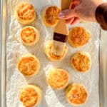 Brushing melted butter on baked butter buttermilk biscuits.