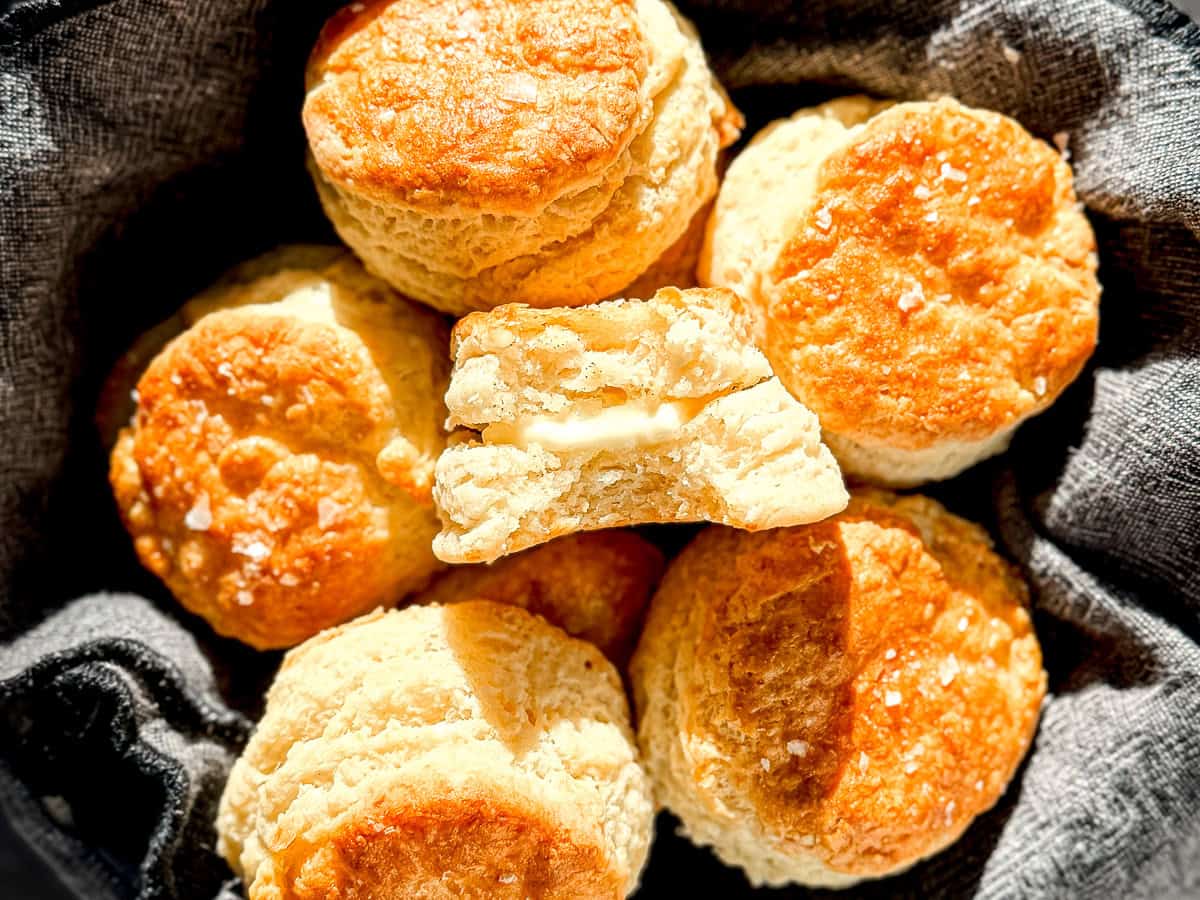 A basket of biscuits, one with butter in the middle.