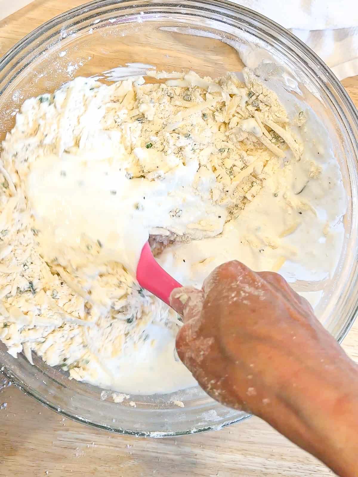 Mixing buttermilk into Gruyere biscuit dough.