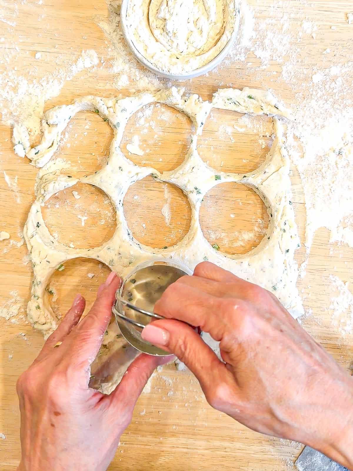 Using a biscuit cutter to cut into biscuit dough.
