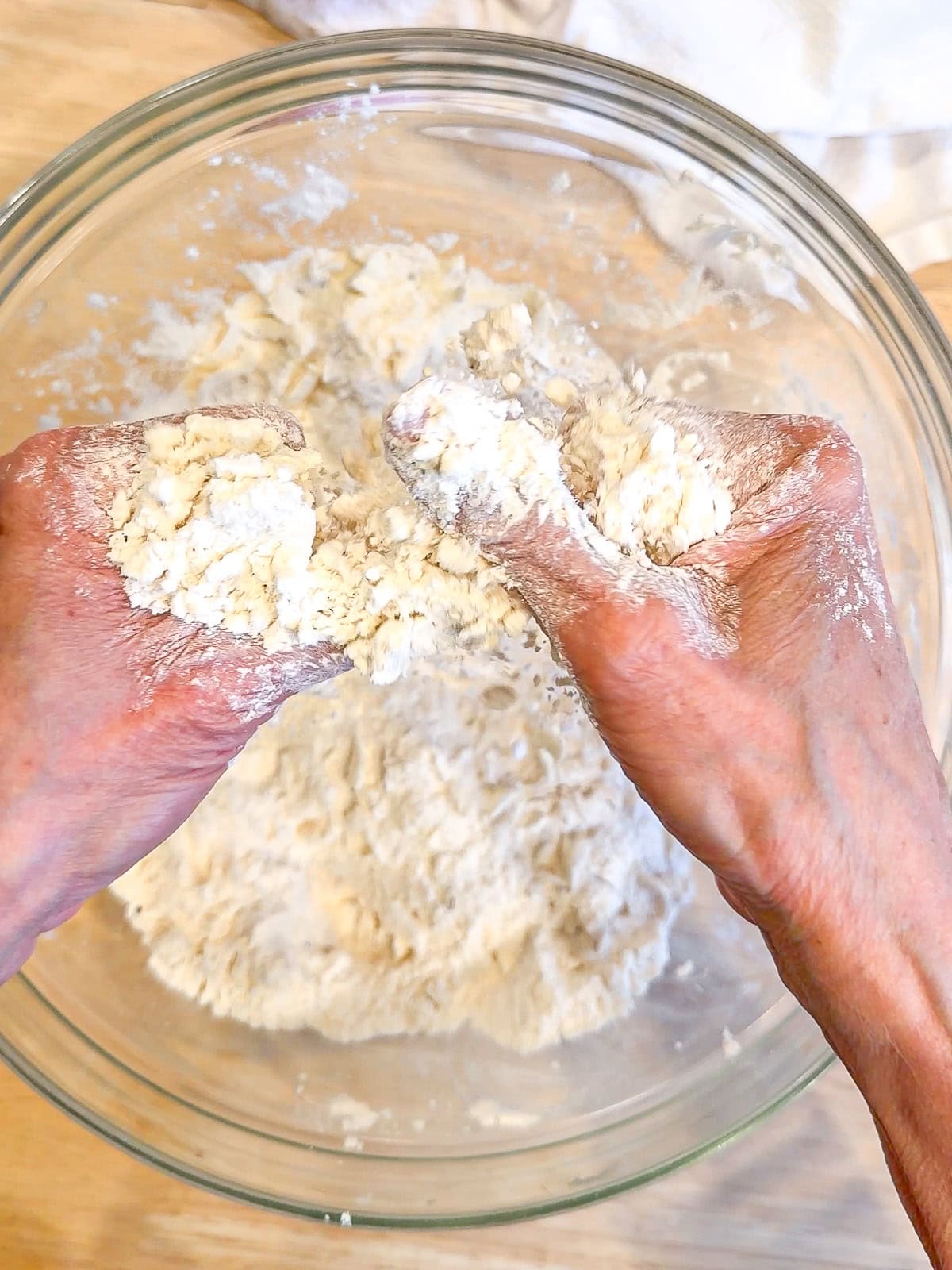 Using fingers to rub butter into flour mixture to make biscuits.