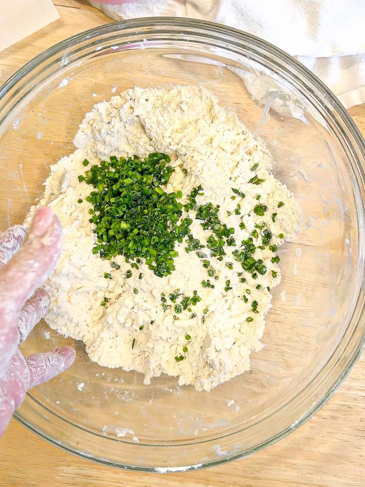 Adding chives to dry ingredients to make biscuits.