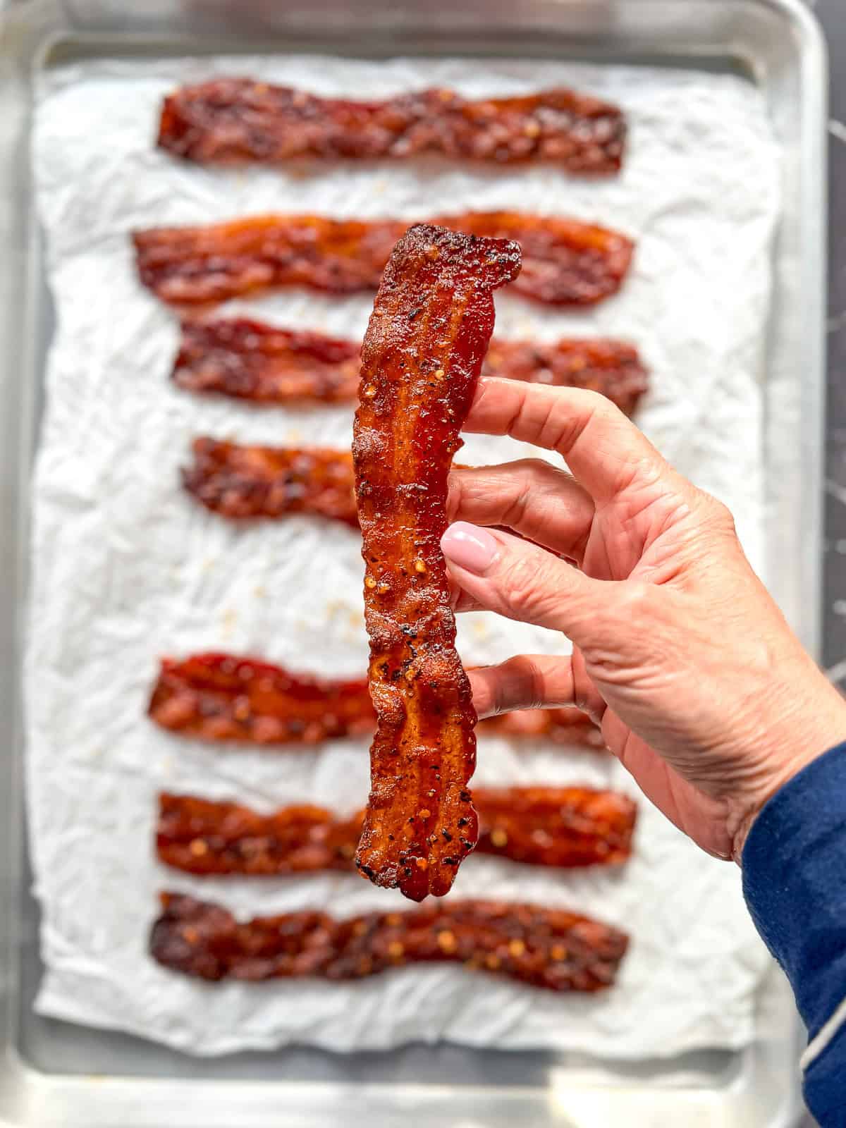 Hand holding a strip of millionaire bacon.