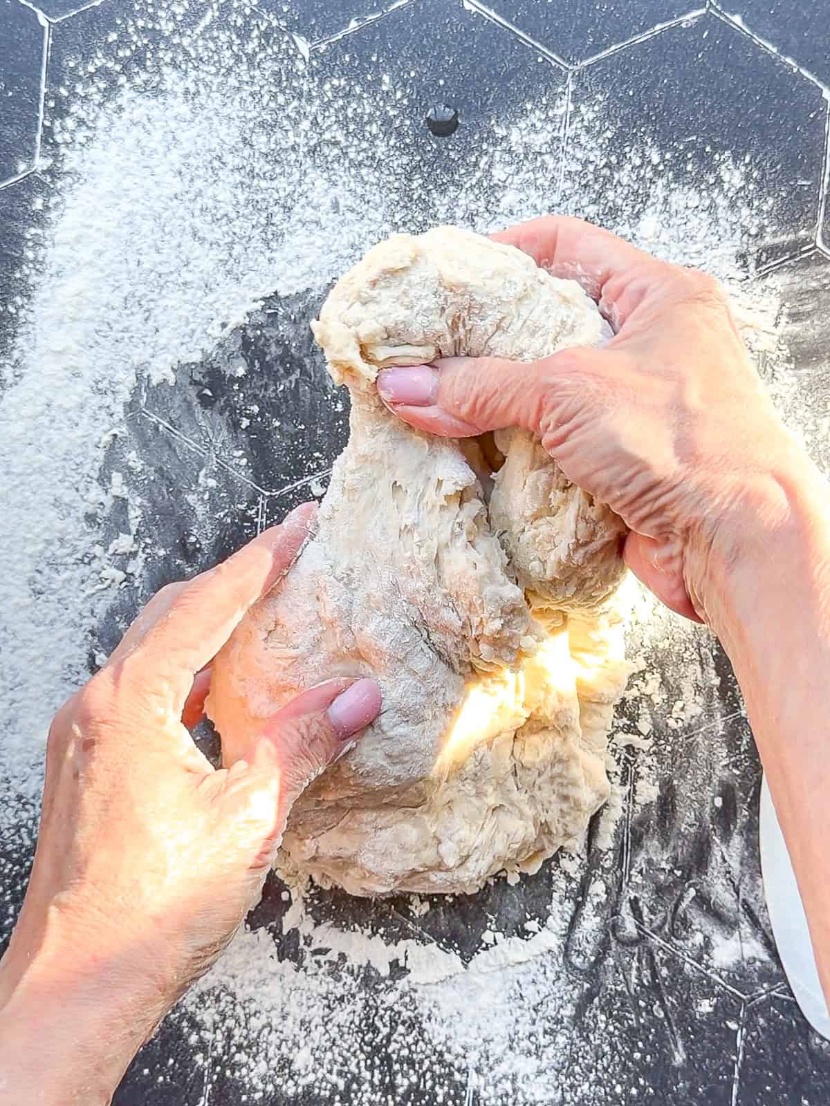 Kneading dough on a black tile counter.