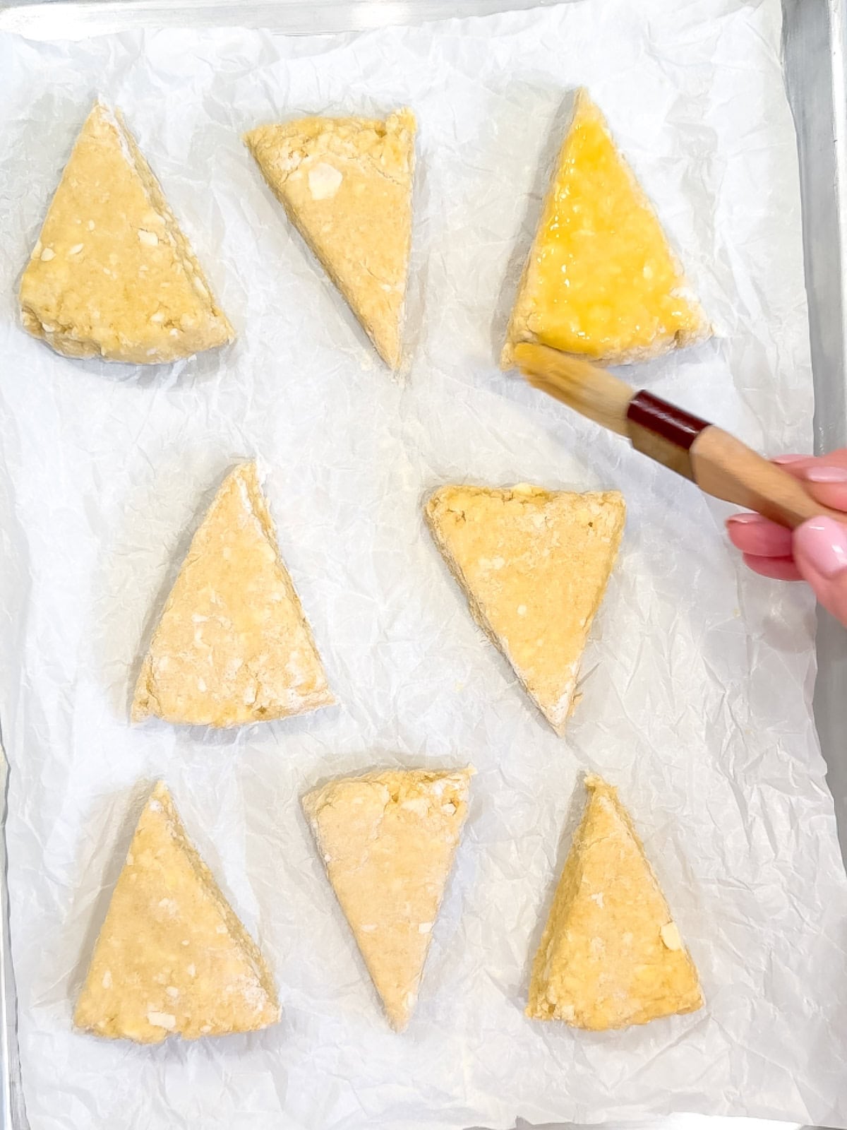 Brushing an egg wash on scone triangles.