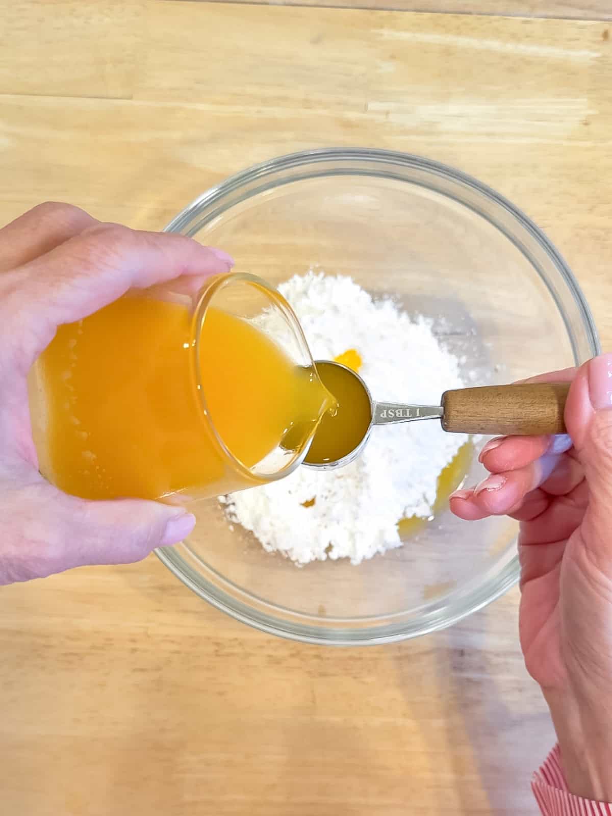 Pouring orange juice into a tablespoon.