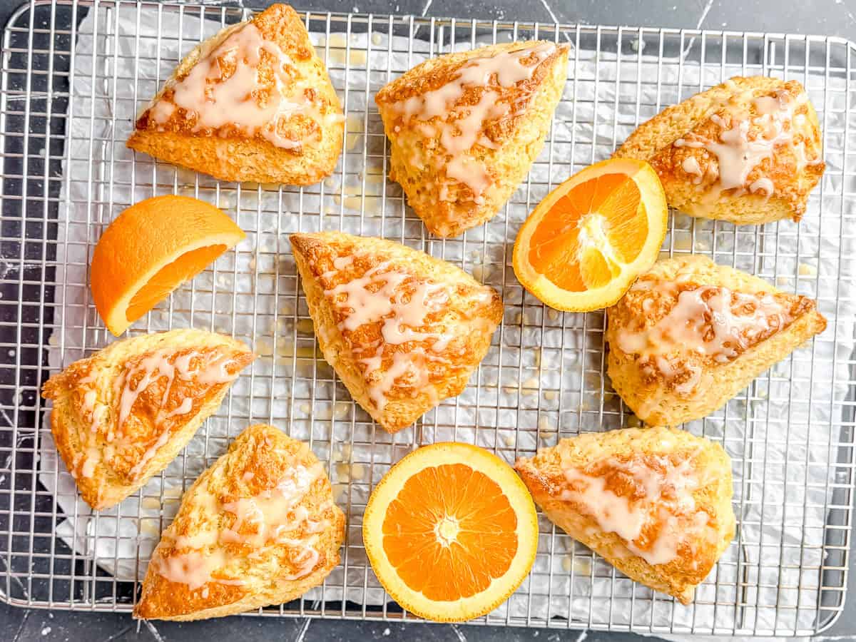 Glazed orange scones on a wire rack with orange slices