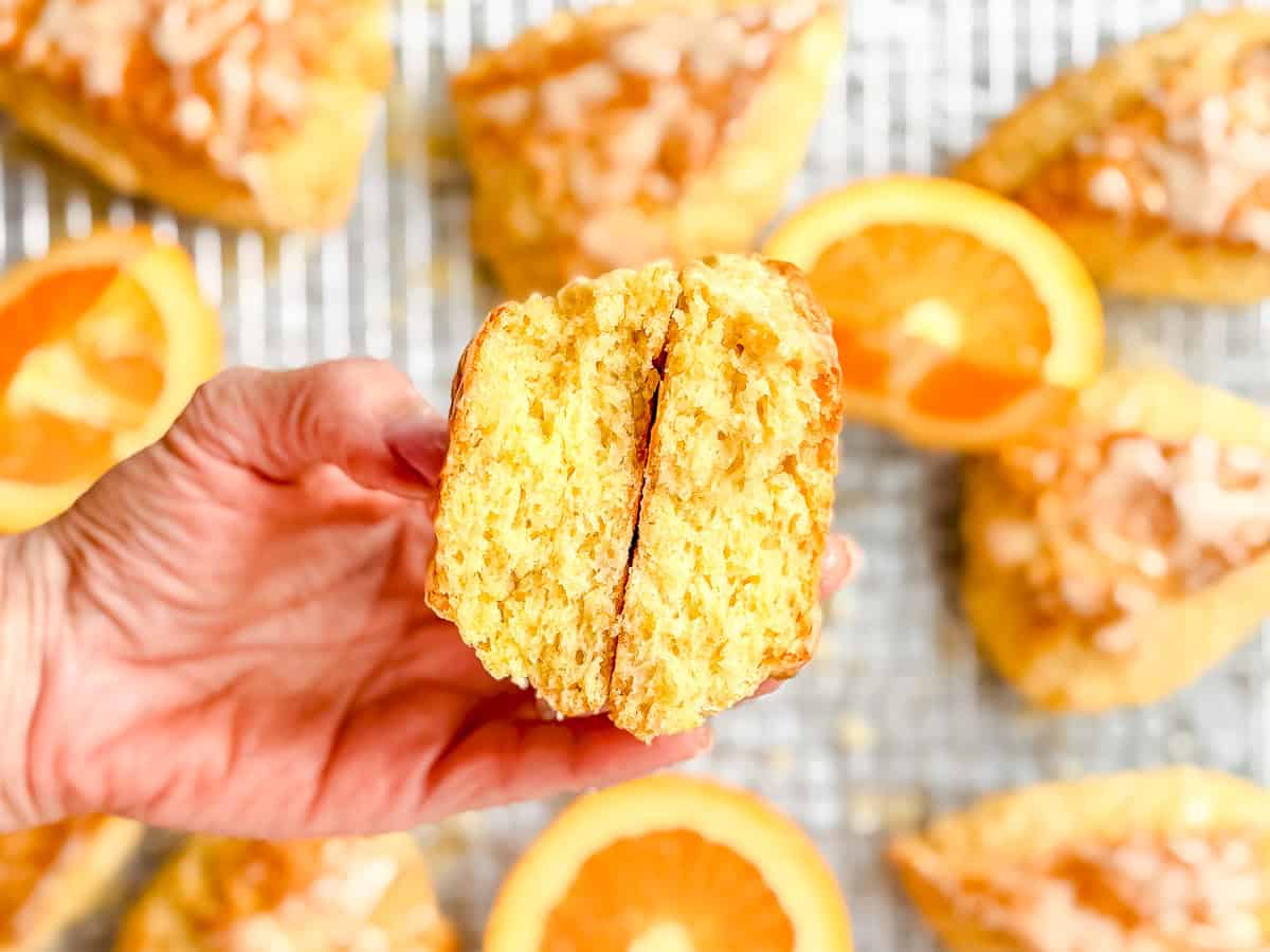 Hand holding a broken open orange scone.