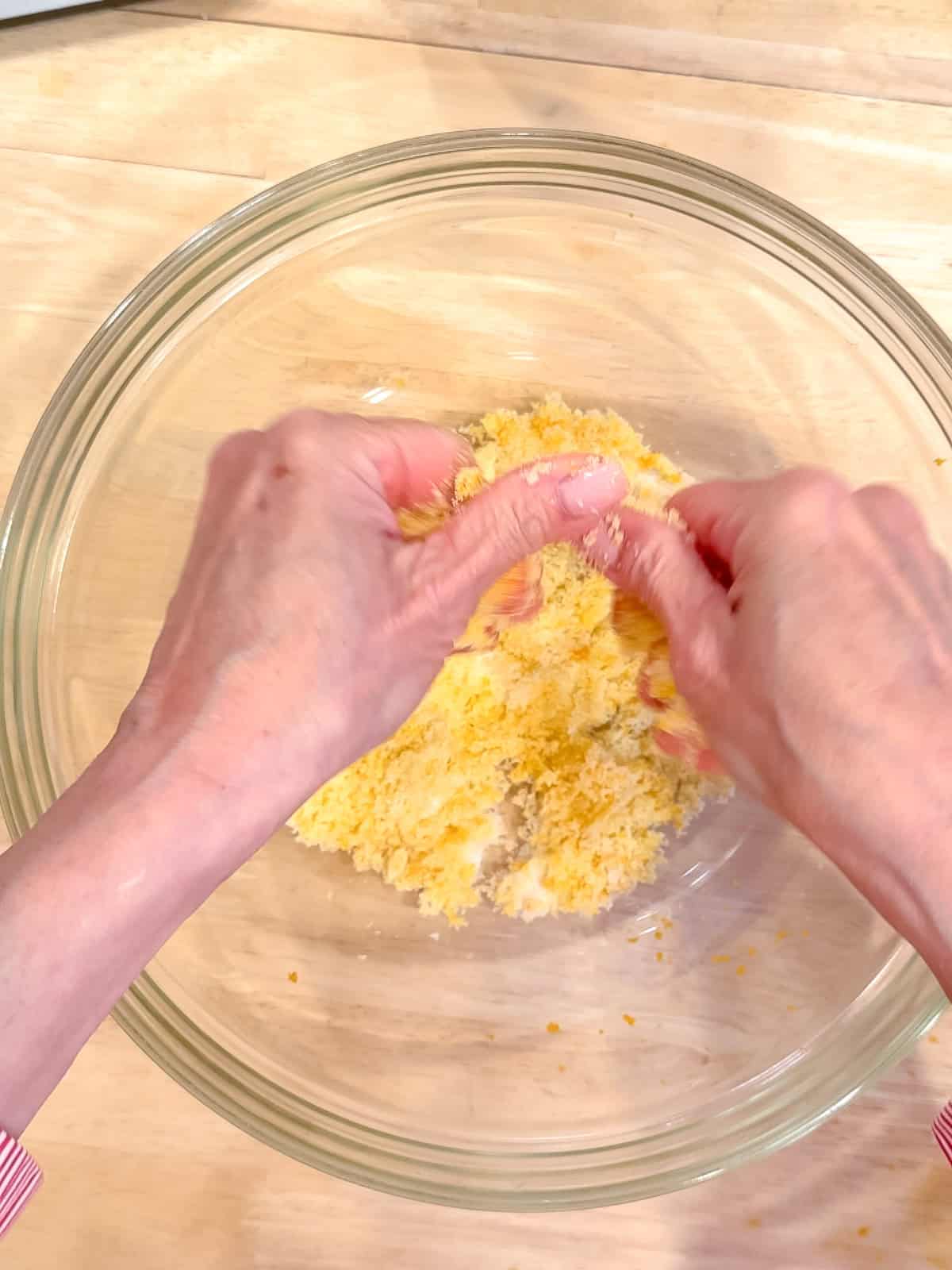 Rubbing orange zest into granulated sugar in a glass bowl.