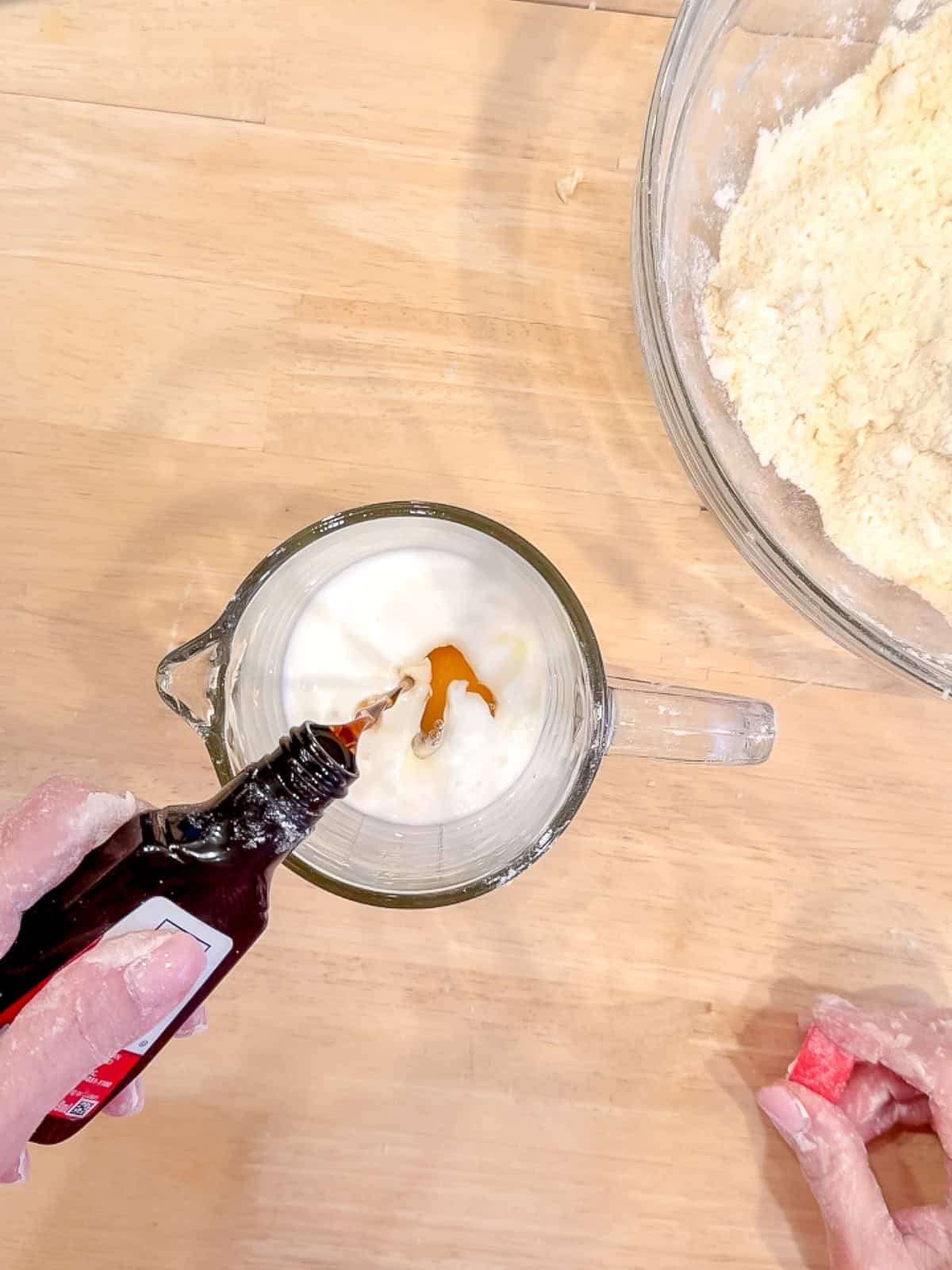 Combining buttermilk, and egg, and vanilla in a glass measuring cup.