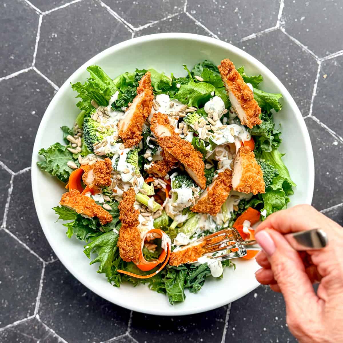 A salad with ranch dressing and chopped chicken strips.