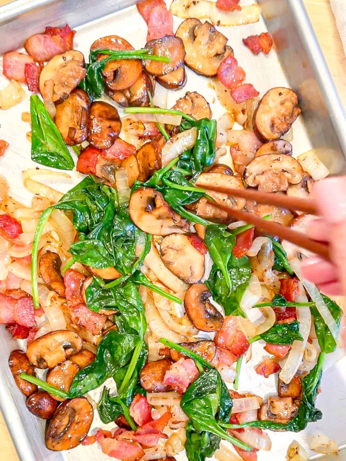Using chopsticks to arrange ingredients on a sheet pan.
