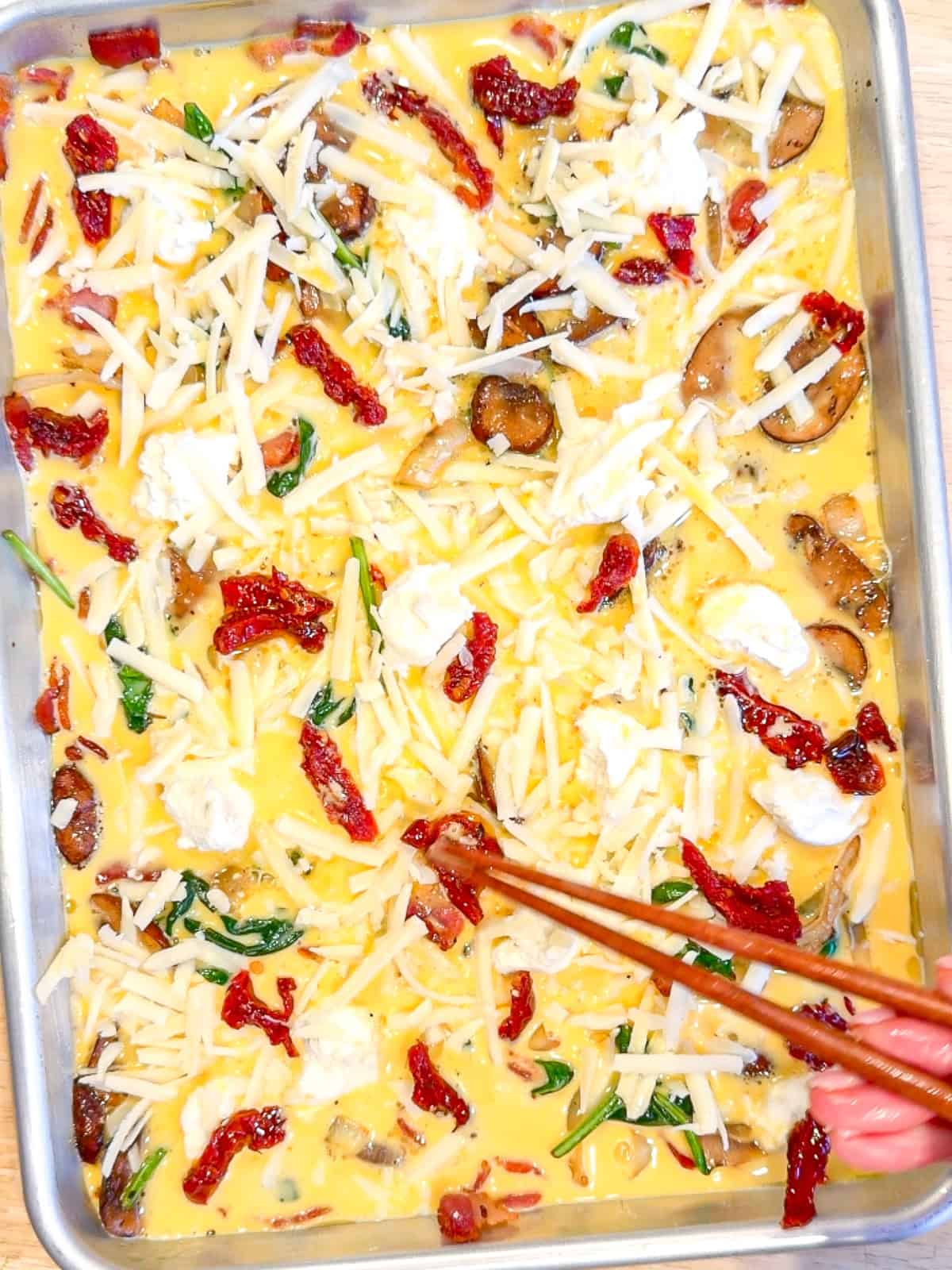 Using chopsticks to arrange ingredients for a sheet pan frittata.