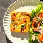Frittata with a side salad on a tan scalloped plate.